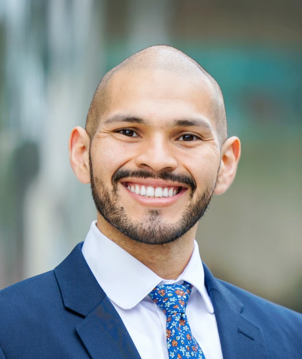 Headshot of a man smiling wearing a suit and tie.